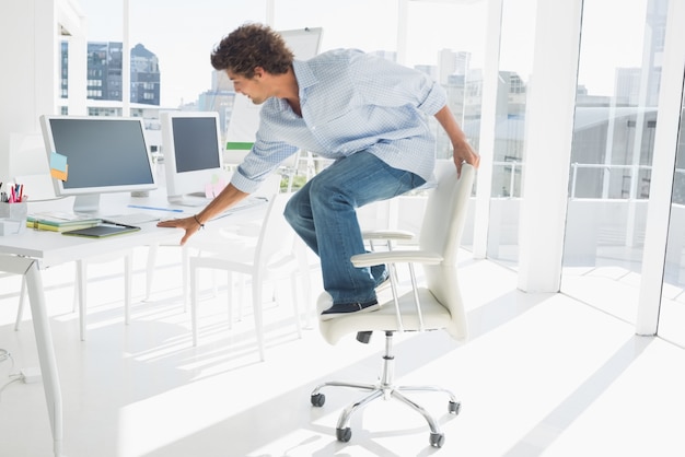 Young man standing over chair in bright office