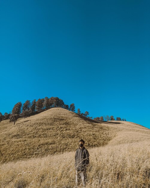 Young man standing on field against sky