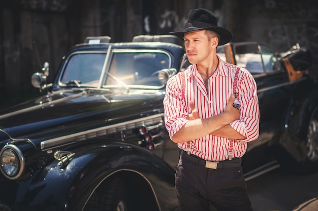 Young man standing in front of black retrostyled car\
outdoors