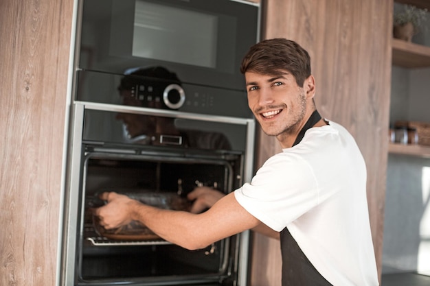 Young man standing near an electric oven in the home kitchen