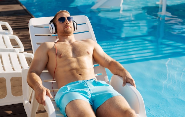 Young man standing near swimming pool having a great time