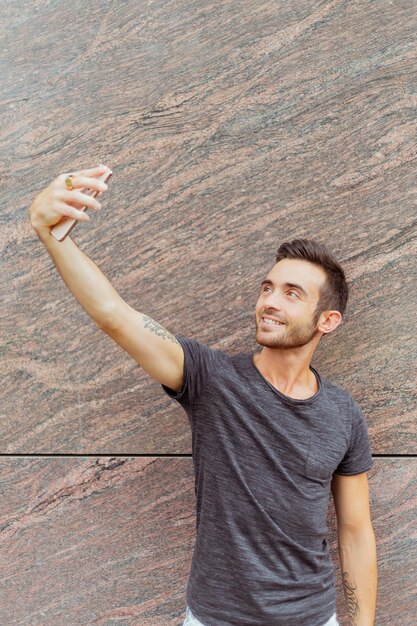 Photo young man standing outdoors while taking selfie