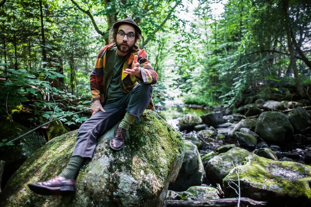 Молодой человек, стоящий на скале в лесу.