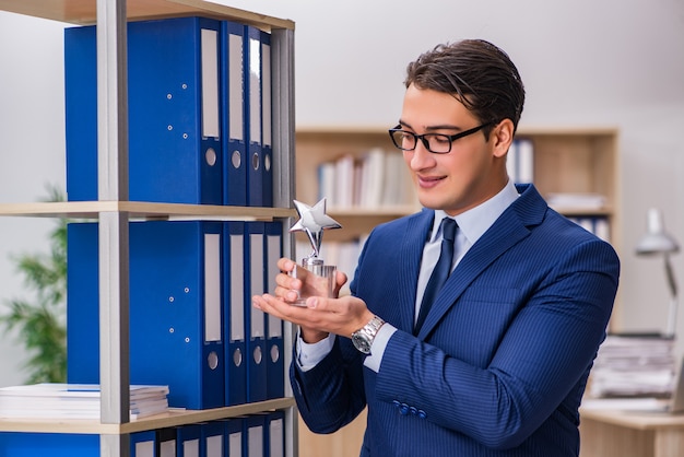 Young man standing next to the shelf with folders