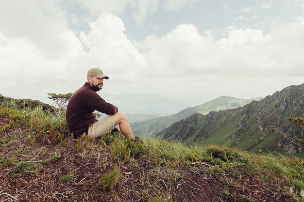 Young man standing on top of cliff enjoying view of nature