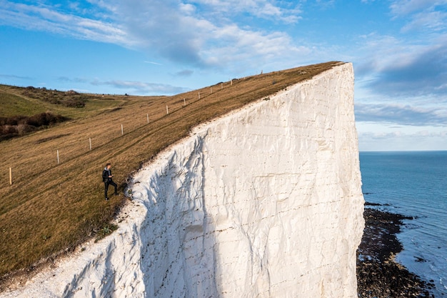 도버의 화이트 클리프 위에 서 있는 젊은 남자. 바다 쪽에서 절벽의 보기를 닫습니다. 잉글랜드, 이스트 서식스. 프랑스와 영국 사이