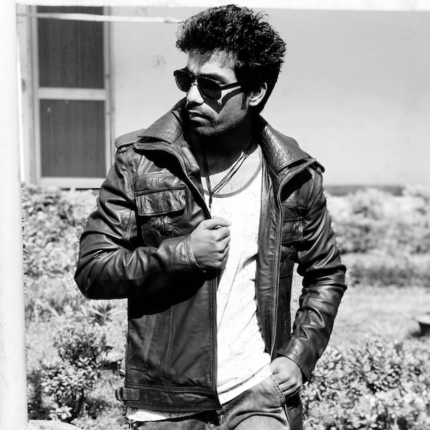 Photo young man standing wearing leather jacket and sunglasses against house