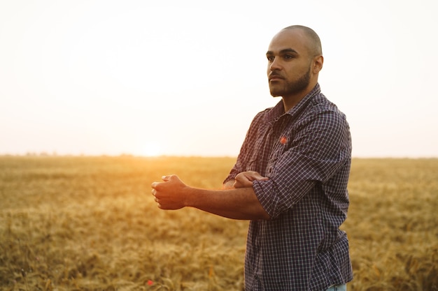 Young man standing in wheat field on sunset