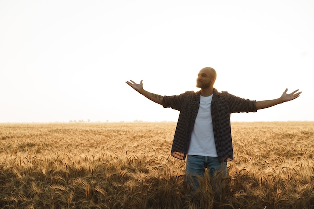 Young man standing in wheat field on sunset