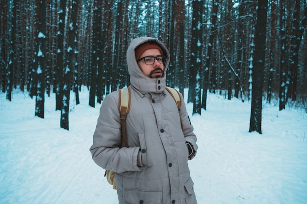 Young man standing in winter snowy forest