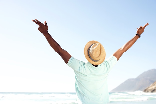 Young man standing with arms spread open at beach