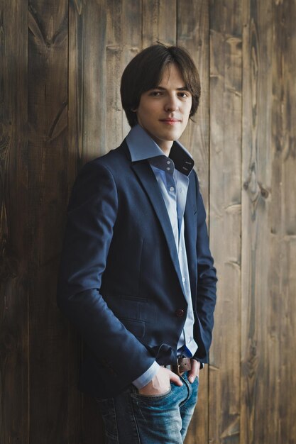 A young man stands on a background of a wooden wall 5447