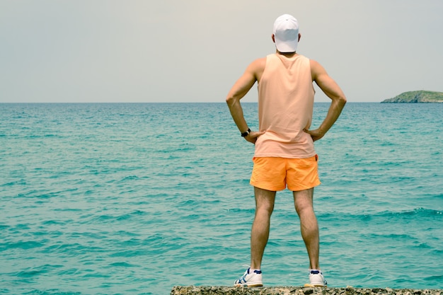 A young man stands on the edge of the pier, looks into the distance