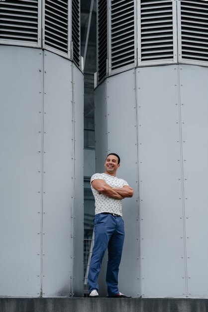 A young man stands in front of technical structures and looks into the distance with a piercing gaze.