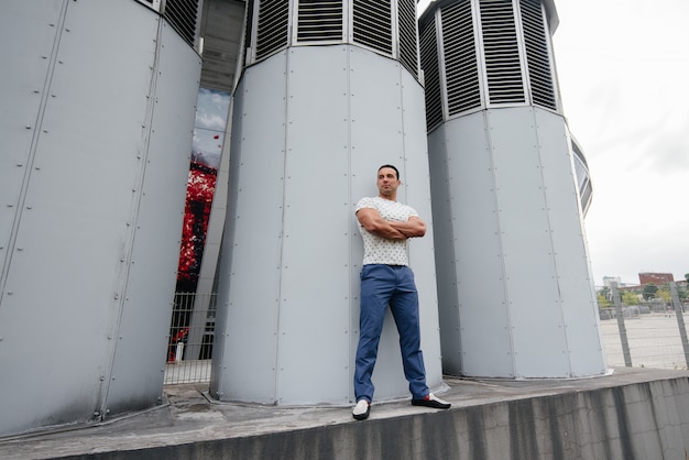 A young man stands in the open air near technical structures.