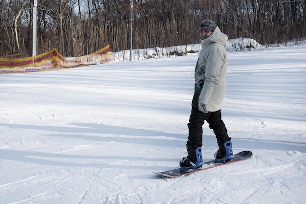 Foto un giovane si trova su uno snowboard in cima a una pista da sci innevata e si prepara a scendere snowboarder prima della discesa sport invernali estremi vacanza in una stazione sciistica copia spazio