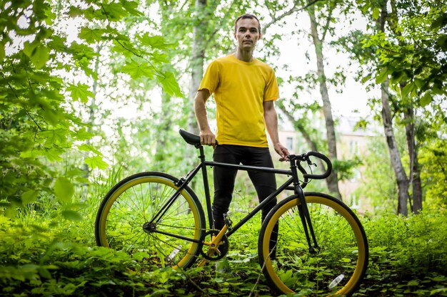 若い男が公共の公園で自転車で休むのをやめた