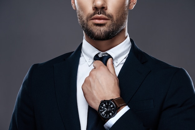 Young man straightens his tie, his face unshaven.