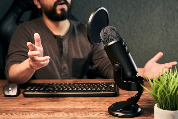Photo young man streamer talking on a microphone in a homemade studio