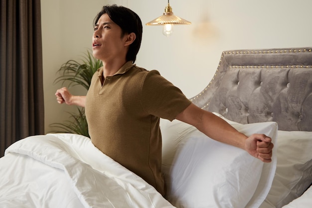 Young Man Stretching in Bed