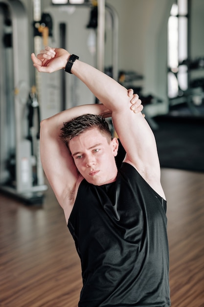 Young man stretching in gym