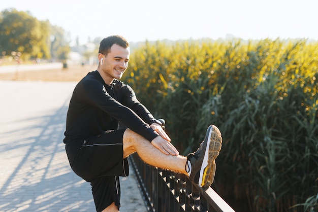 Young man stretching outside in the park after some running circles.