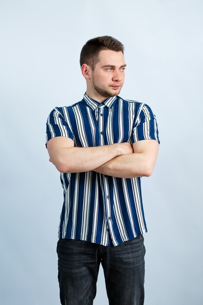 Young man in a striped classic shirt over white wall