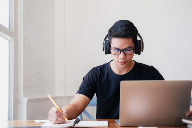 Молодой человек учится дома с помощью ноутбука и обучения в Интернете