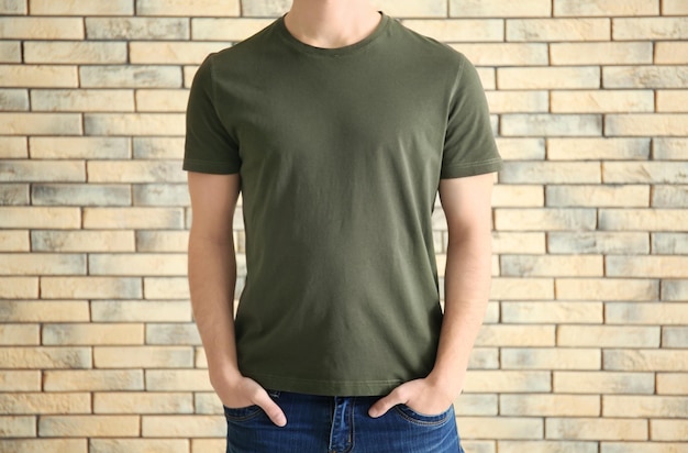 Young man in stylish tshirt against brick wall Mockup for design
