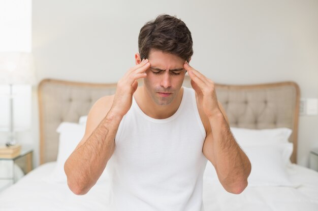 Young man suffering from headache in bed