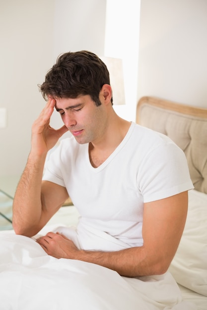 Young man suffering from headache in bed