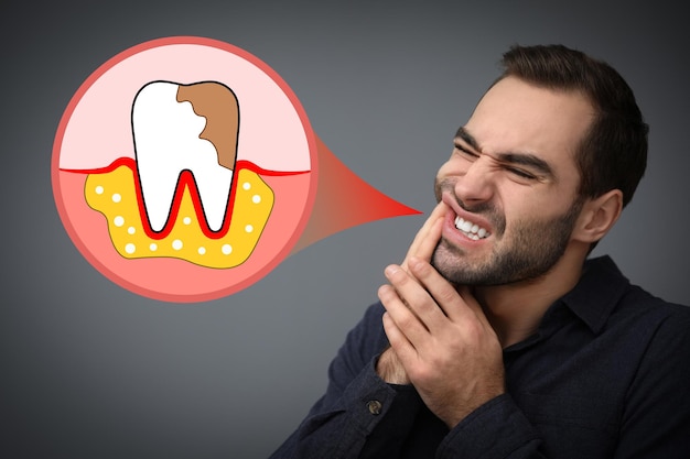 Young man suffering from toothache on grey background