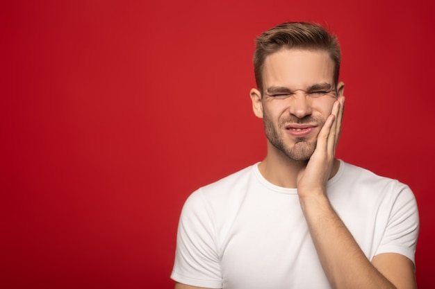 young man suffering from toothache isolated on red