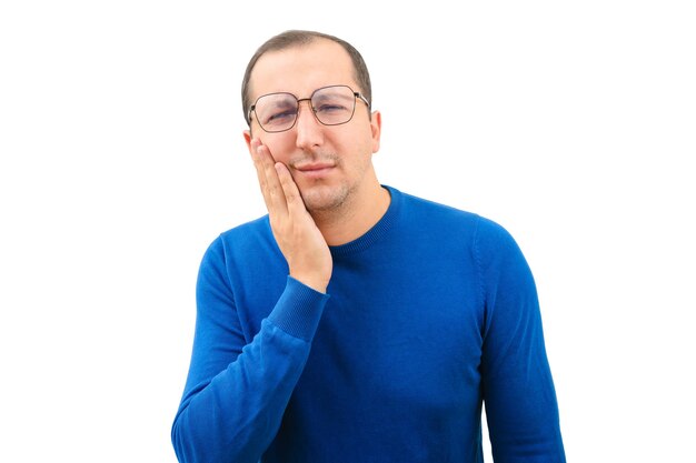 Young man suffering from toothache touching cheek on white background