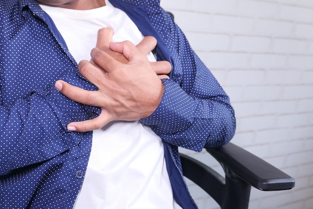 Young man suffering pain in heart and holding chest with hand