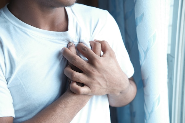 Foto giovane che soffre di dolore al cuore e tenendo il petto con la mano