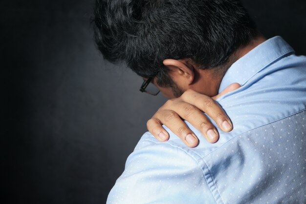 Young man suffering shoulder pain isolated on black.