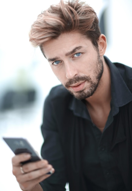 Young man in suit standing in urban environment and messaging