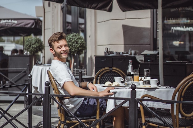 young man in a summer cafe on the terrace has breakfast