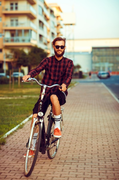Young man in sunglasses riding a bike on city street