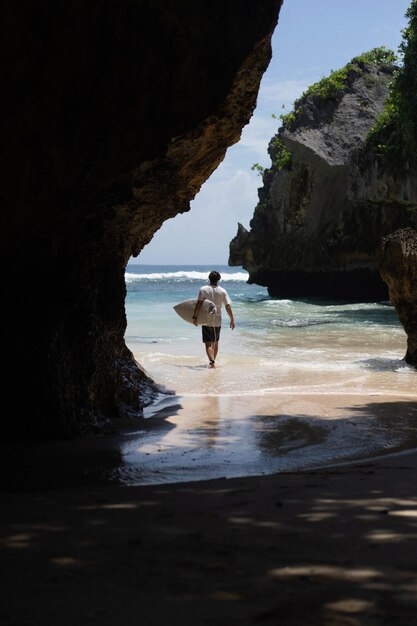 Young man surfer with surfboard on the ocean, uluwatu surfspot.