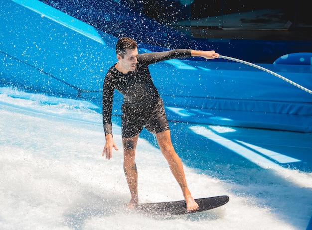 Young man surfing on a wave simulator at a water amusement park