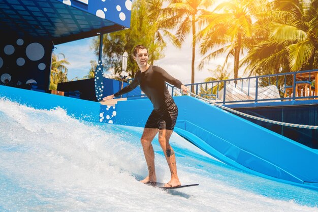 Young man surfing on a wave simulator at a water amusement park