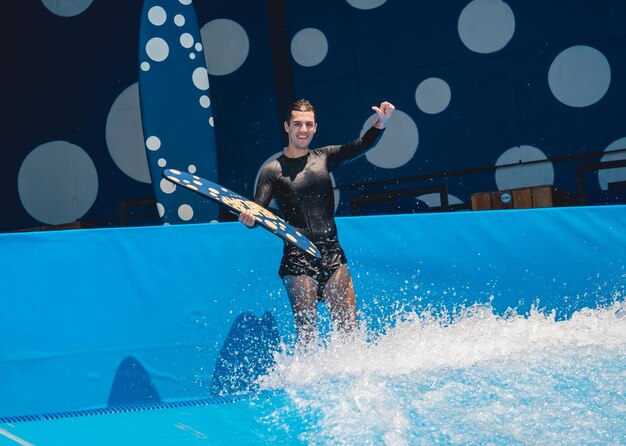 Young man surfing on a wave simulator at a water amusement park