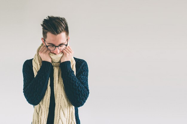 Young man in sweater feel cold over a white background