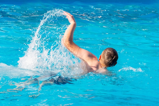 Young man swimming in the pool. Rest in the summer at the resort 