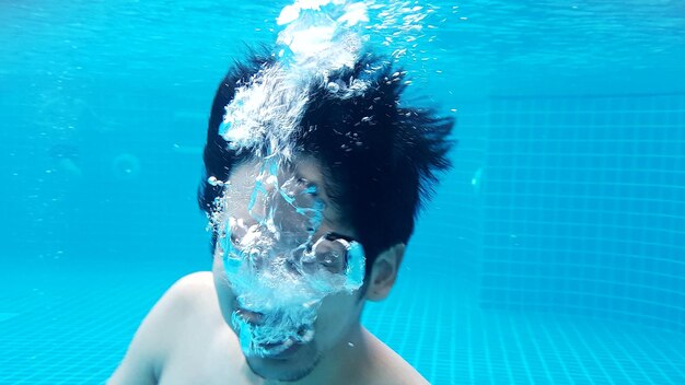 Young man swimming underwater in pool