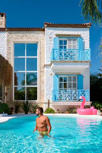 Young man at an swimmingpool with red pink flamingopink flaming by the pool