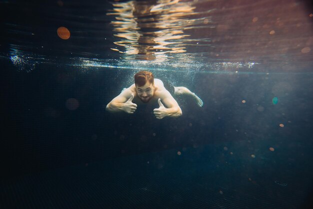 若い男が水中のプールで泳いでいます休暇と心配のない生活のコンセプト