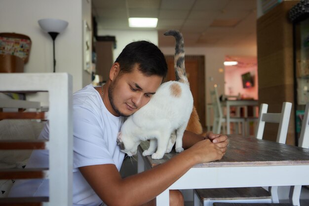 Молодой человек в футболке держит кошку